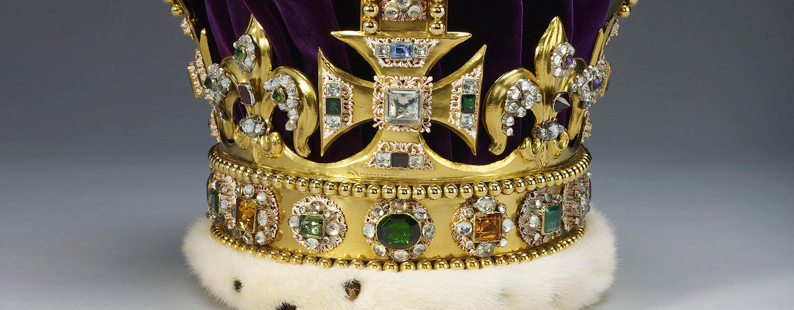 Золотая корона украшена бриллиантами, рубинами, аметистами и сапфирами.  У него фиолетовая бархатная шапочка.