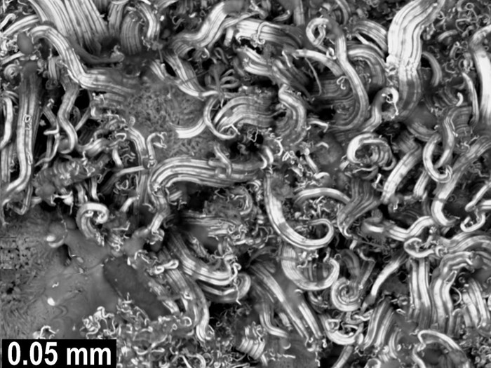 Крайне микроскопический крупный план серебряных спиралей, сложенных вместе, как волны в бурном океане.