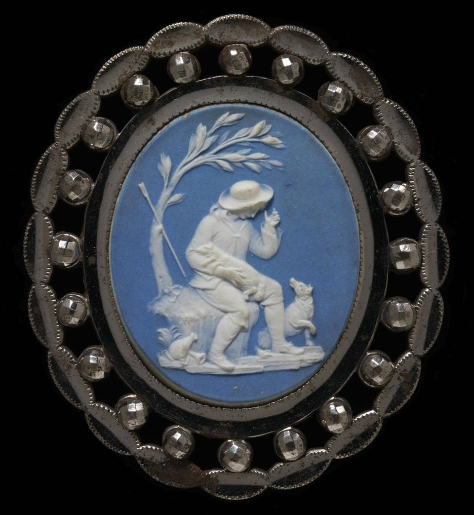 Овальная брошь из ограненной и отполированной стали, украшенная пластиной из голубой яшмы с белой камеей, изображающей пастушка, сидящего под деревом с ягненком на руках и собакой у его ног.