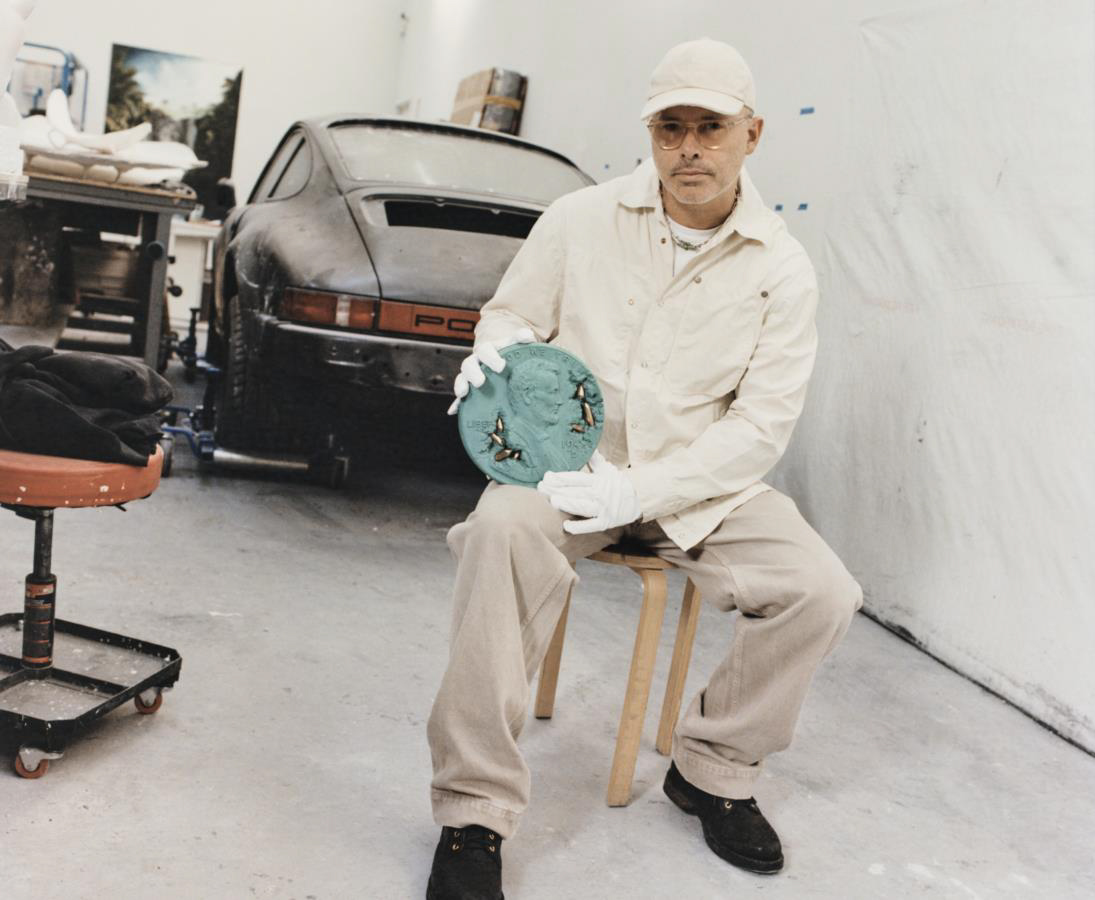 Дэниел Аршам держит скульптуру «Бронзовый разъеденный пенни-сосуд»