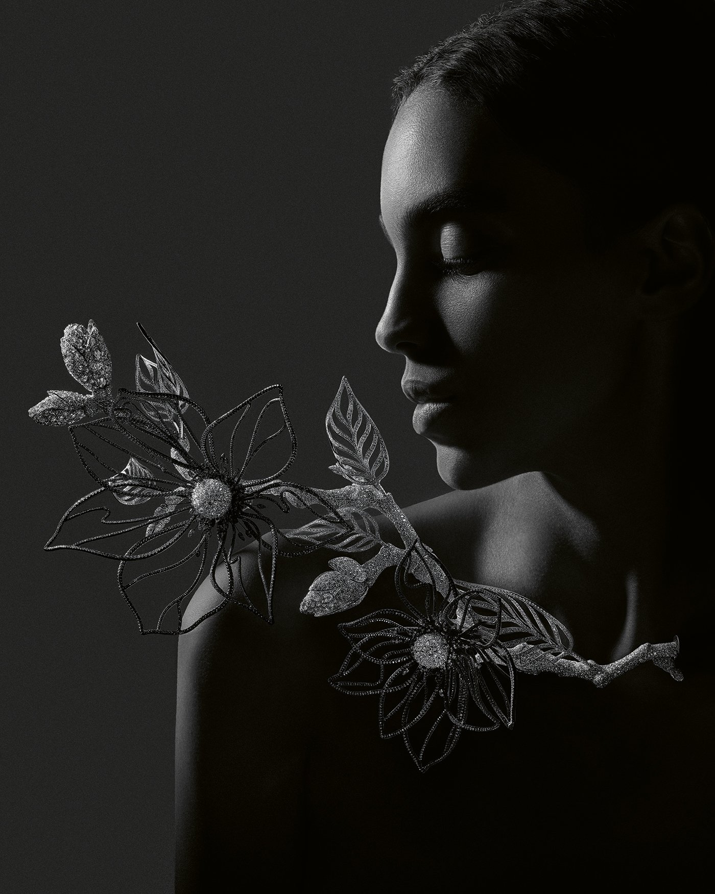 Колье Boucheron «Магнолия», композиция № 2. Мастера отсканировали настоящее дерево магнолии, включая его ветви, цветы и бутоны, чтобы создать это алюминиевое изделие. Линейная инкрустация бриллиантами заставляет алюминиевые лепестки, покрытые черной керамикой, сверкать, а сердцевина цветов из белого золота инкрустирована перевернутыми бриллиантами. Палочник выполнен из белого золота, украшенного бриллиантами. Ваза изготовлена ​​из матового черного композитного материала.